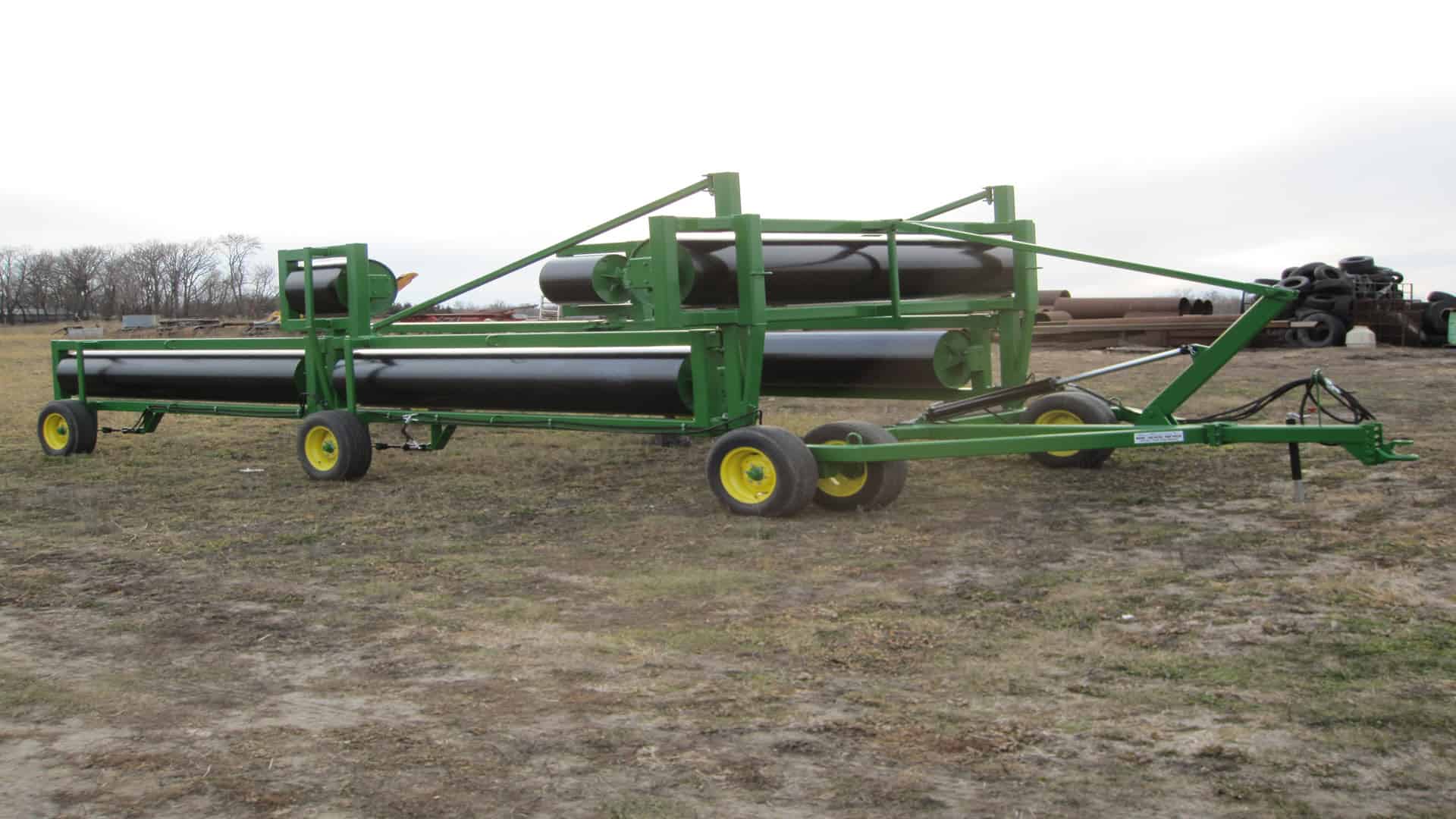 Agricultural crop sprayer trailer with black tanks and green frame.