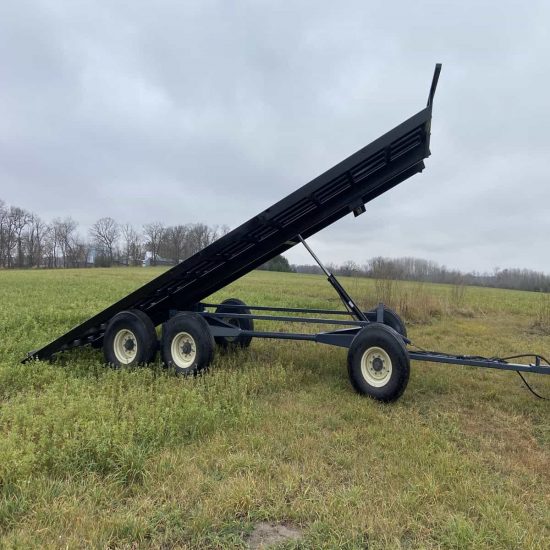 Farm dump trailer with dual wheels, black steel build, ideal for heavy agricultural loads and field work.